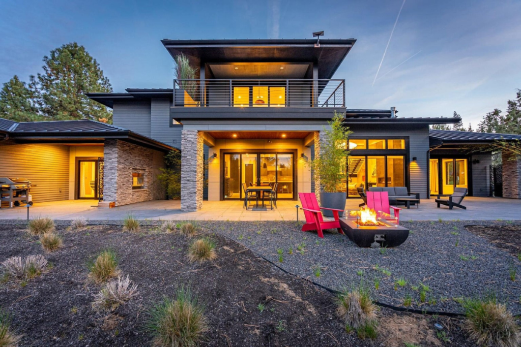 Contemporary Central Oregon home with expansive windows and outdoor fire feature at dusk