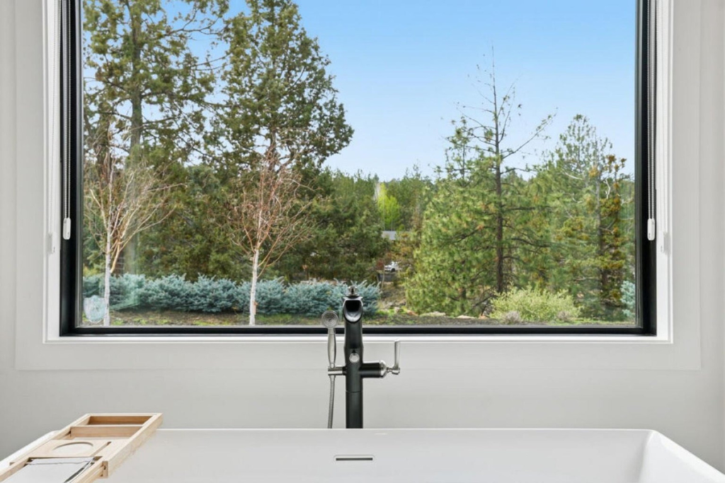 Soaking tub beneath a picture window with views of native Central Oregon landscaping