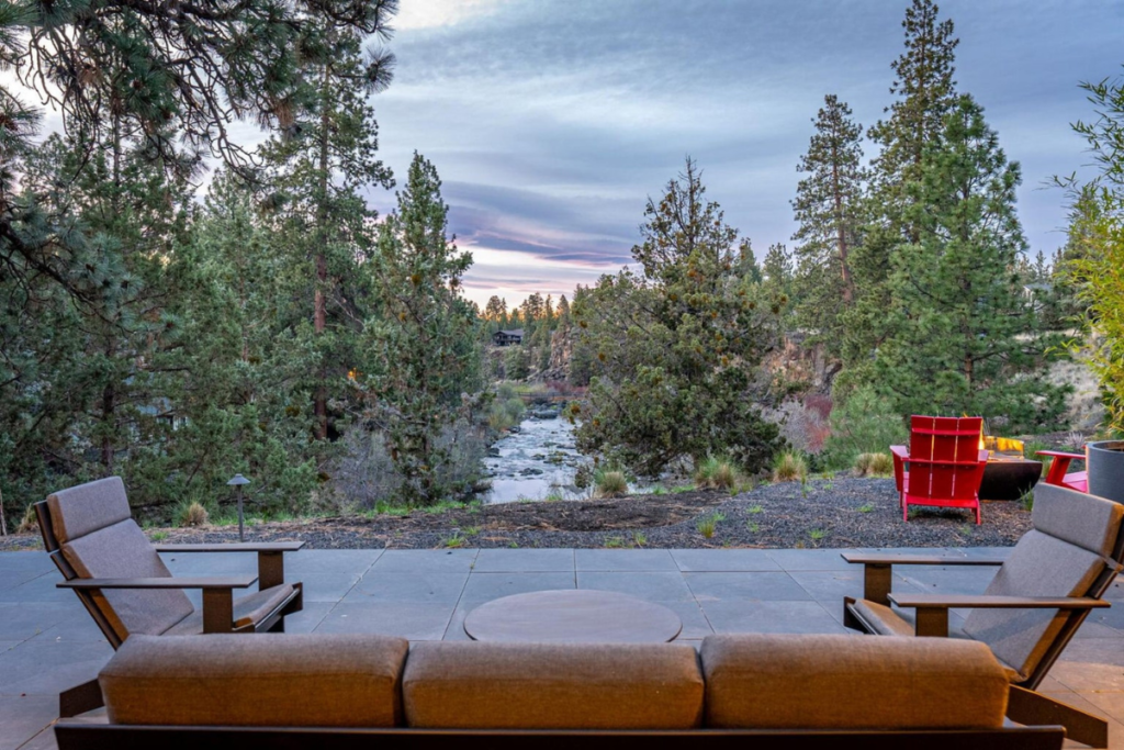 Outdoor living area overlooking the Deschutes River with ponderosa pines and a fire feature
