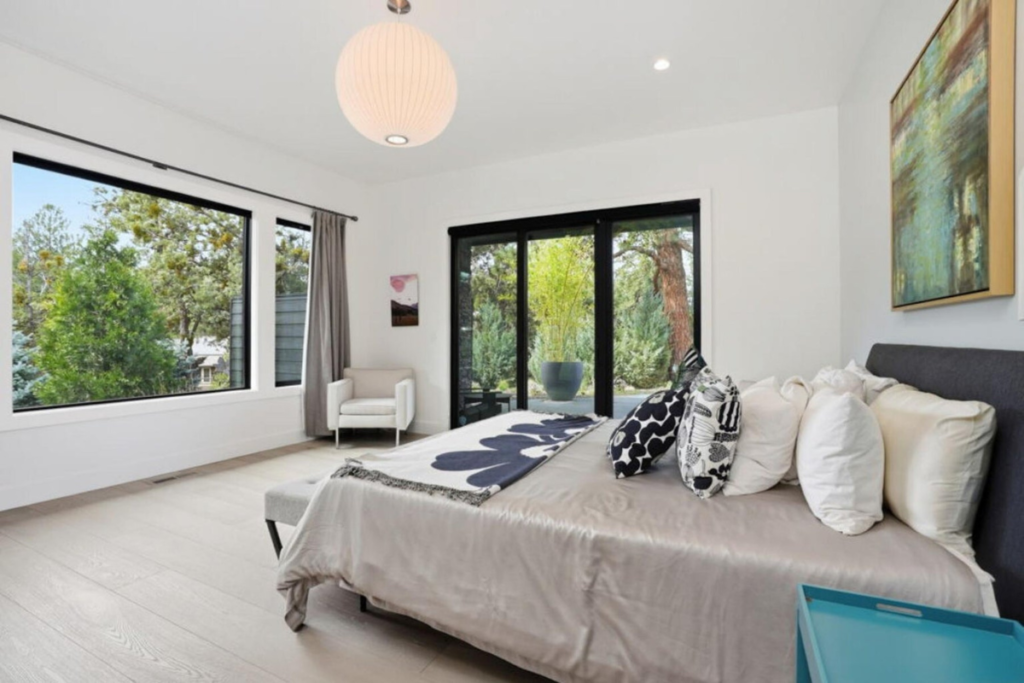 Modern primary bedroom with large windows and direct connection to the surrounding landscape