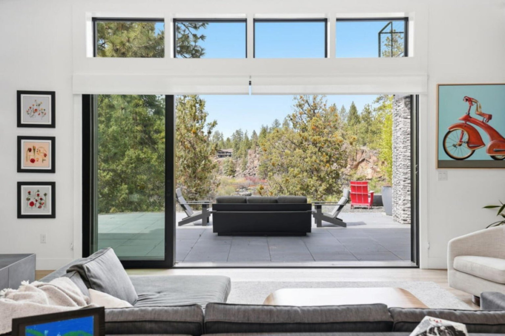 Living room opening to a private outdoor patio surrounded by the Central Oregon landscape